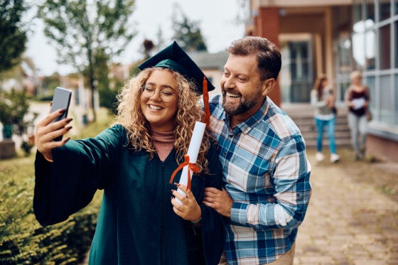 Happy student taking selfie with her father on her graduation day