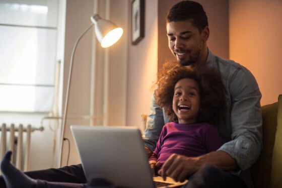 Father and daughter excitedly looking at laptop