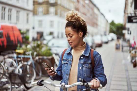 Woman with phone and bike navigating downtown