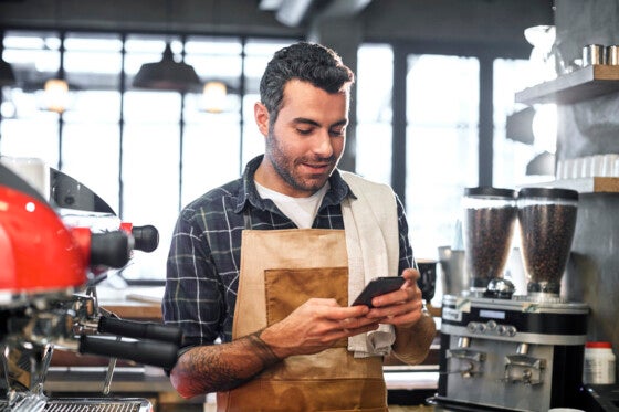 Cafe owner managing finances from his phone
