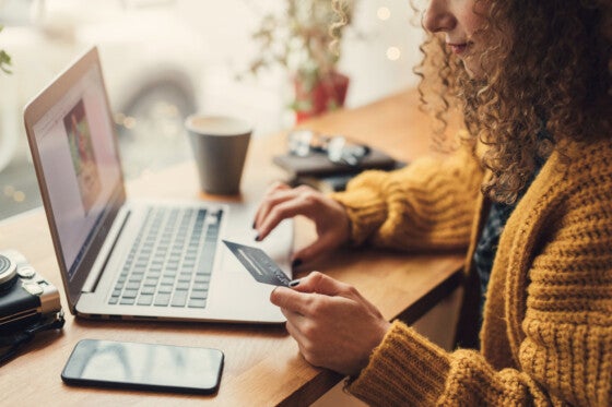 Woman in cafe using credit card and laptop
