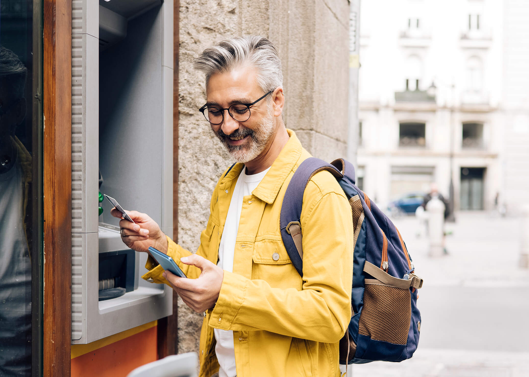 Man in a yellow jacket using an atm