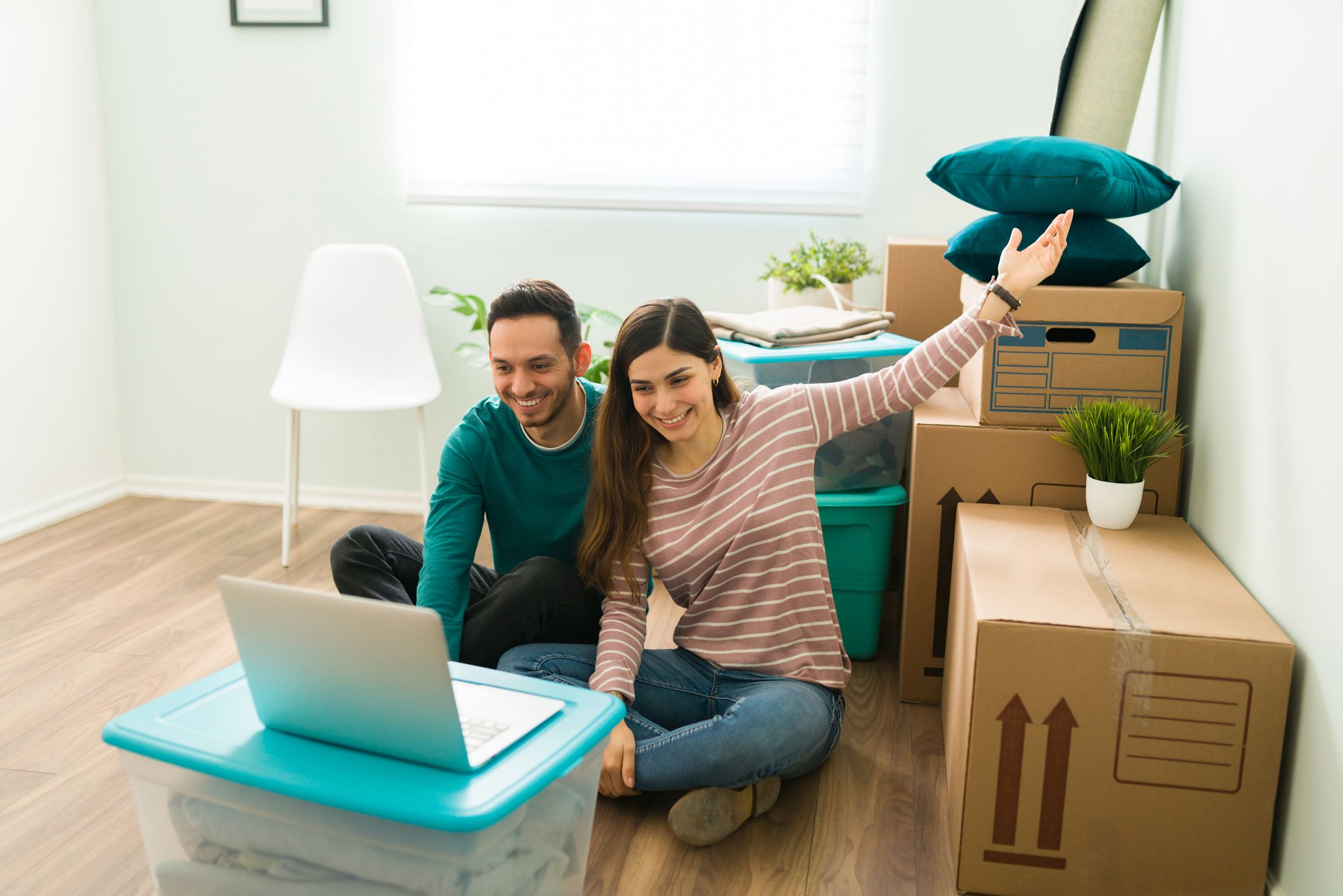 Happy newlyweds just moved into a new home. Excited couple showing their loved ones their living room with packed cardboard boxes