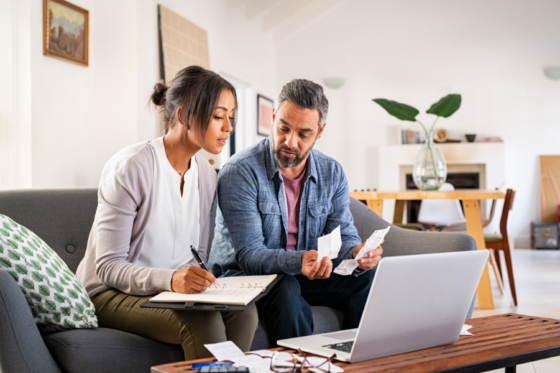 Couple sitting in living room with laptop creating 60 30 10 rule budget.