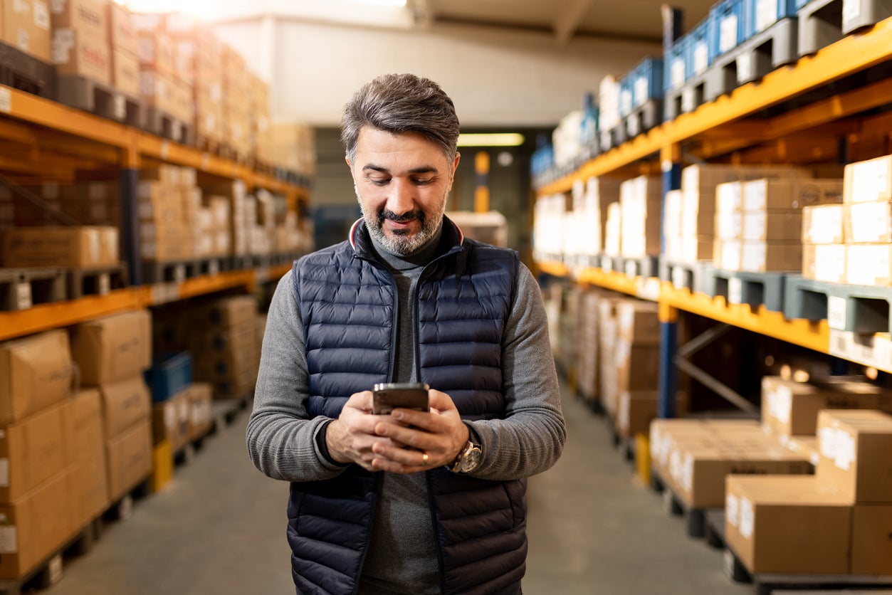 Male business owner standing in warehouse looking at short term vs long term loans.