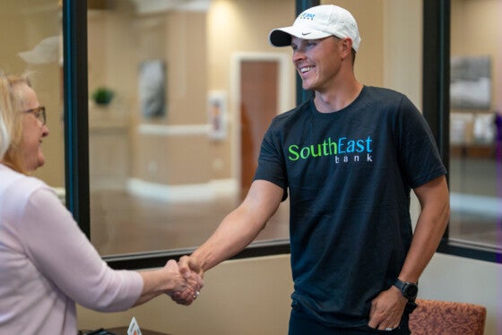 trevor bayne shaking southeast bank employees hand after opening a checking account