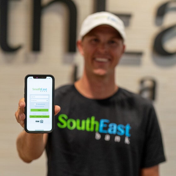 Trevor bayne holding southeast bank mobile banking app on his phone