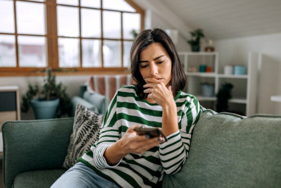 Concerned young woman using smart phone in a living room