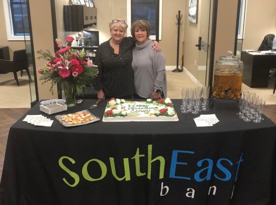 Two women behind a retirement party spread