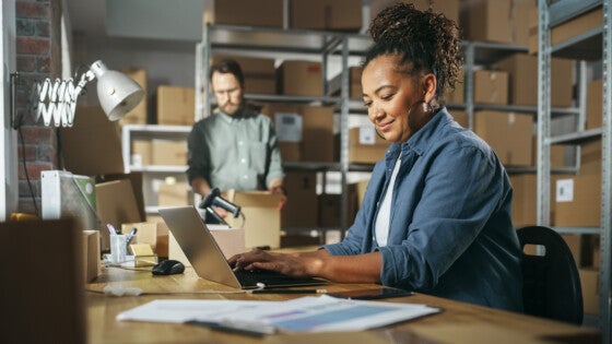 Workers in warehouse packing products and reviewing financial documents