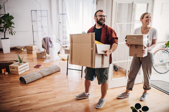 Two people, young couple carrying boxes together in their new home