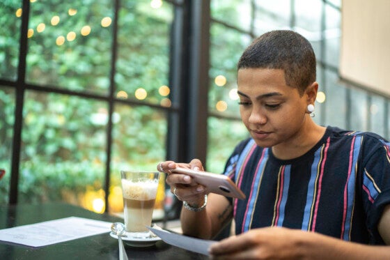 Young woman depositing check by phone in a cafe