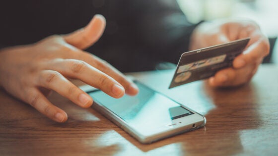 Using mobile phone with debit card in hand