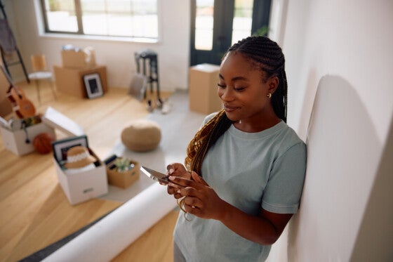 Happy African American woman using smart phone in her new apartment.