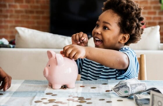 Black boy collecting money in a piggy bank